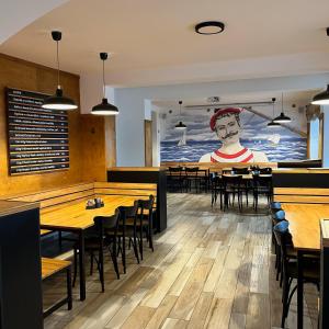 a dining room with tables and a large mural of a man at Hotel U námořníka in Plzeň