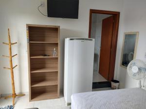 een witte koelkast in een kamer met een tv bij Hostel Pousada Casa da Praia in Passo de Torres