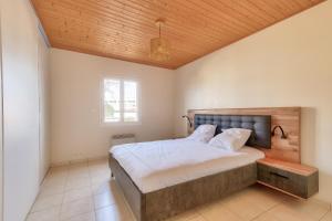 a bedroom with a large bed and a wooden ceiling at Maison moderne 2 chambres avec piscine commune in Les Sables-d'Olonne