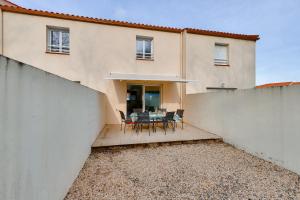 une maison avec un patio avec une table et des chaises dans l'établissement Maison moderne et piscine commune, à Les Sables-dʼOlonne