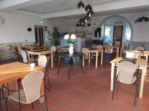 a dining room with tables and chairs and a kitchen at Le Castel d'olmes in Laroque-dʼOlmes