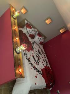sypialnia z łóżkiem z białymi i czerwonymi poduszkami w obiekcie La nuit glamour w mieście Herblay