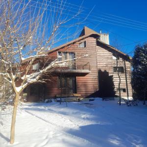 a wooden house with a deck in the snow at podkornutami in Sękowa