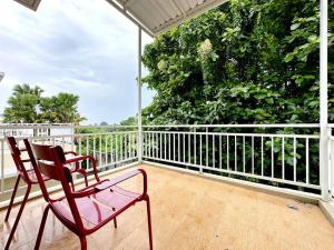 a balcony with a red chair on a porch at Villa Blue Saphire Sanur Mansion Bali in Denpasar