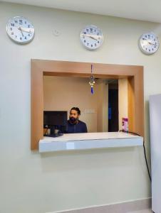 Ein Mann steht vor einem Spiegel mit Uhren. in der Unterkunft GRACE INN GUEST HOUSE, Near Airport and Ion Digital in Guwahati