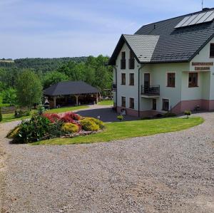 ein großes weißes Haus mit Kieseinfahrt in der Unterkunft Agroturystyka Za Dębem in Łagów