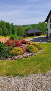 un jardin avec des fleurs colorées devant un bâtiment dans l'établissement Agroturystyka Za Dębem, à Łagów