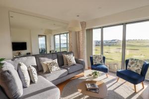 a living room with a gray couch and two blue chairs at Newquay Fistral Beach View in Newquay