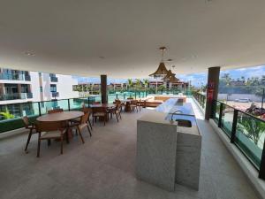 un balcone con tavoli e sedie in un edificio di Makia Beach Experience - D 202 a Porto De Galinhas