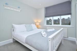a white bedroom with a bed and a window at Hale View by YourStays in Altrincham