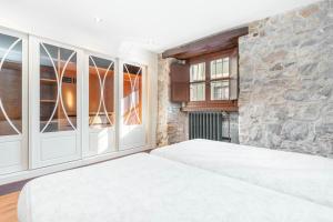 Un dormitorio con dos camas y una pared de piedra. en LA CASA DE LA RIBA, en Luanco