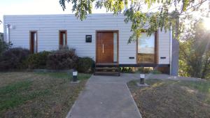 ein kleines weißes Haus mit einer Holztür in der Unterkunft LAS LAVANDAS in Sierra de la Ventana