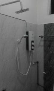 La salle de bains est pourvue d'une douche et d'un tuyau fixé au mur. dans l'établissement Airport Kota Bharu Homestay & Riverview Inn, à Kota Bharu