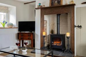 a living room with a fireplace and a table with wine glasses at Tudor Rose Cottage in Stourpaine