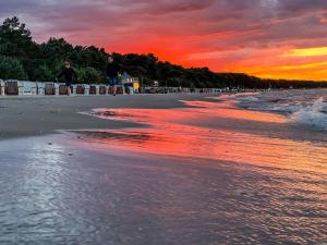 a sunset on the beach with people walking at Ferienwohnung 6 Villa Eden in Binz