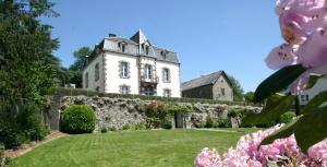 een oud huis aan een muur met bloemen bij Maison d'hôtes et gîtes La Chouannerie à côté du parc du Puy duFou in Pouzauges