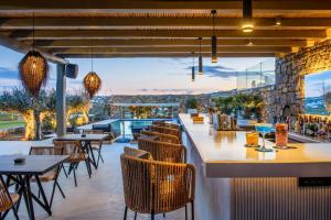 un restaurante con vistas a una piscina, mesas y sillas en Panormos Bay Suites Luxury Resort en Panormos Mykonos