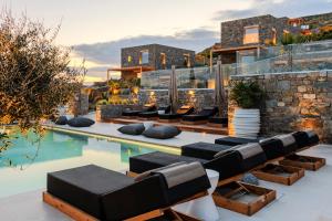 an outdoor patio with lounge chairs and a swimming pool at Panormos Bay Suites Luxury Resort in Mykonos