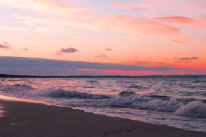 einen Sonnenuntergang über dem Meer mit Wellen am Strand in der Unterkunft Ferienwohnung Meeresbrise in Binz