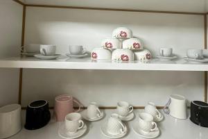 a shelf with cups and saucers and a cake at شقة في الشارقة in Sharjah