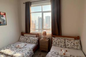 zwei Betten in einem Schlafzimmer mit Fenster in der Unterkunft شقة في الشارقة in Schardscha