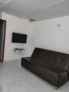 un sofá negro en una habitación blanca con TV en Apartamento, Casa en Buga - Valle, 