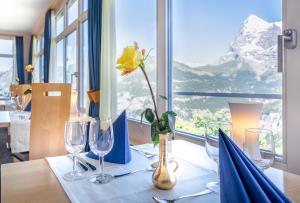 a table with a yellow flower in a vase on it at Hotel Alpina in Mürren