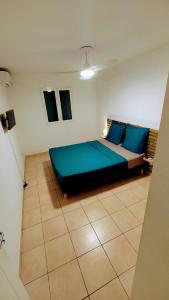 ein Schlafzimmer mit einem Bett mit blauen Kissen darauf in der Unterkunft Les Héliconias Résidence cosy et calme in Les Abymes
