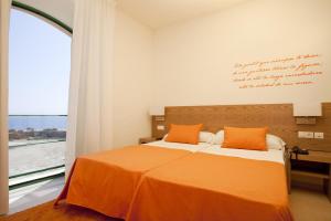 a bedroom with a bed with orange sheets and a window at Boutique Isla Tabarca in Tabarca