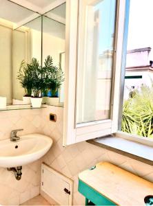 uma casa de banho com um lavatório e uma janela com plantas em Case Calliope em Palermo
