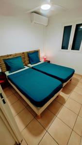 Cette chambre comprend un grand lit avec des oreillers bleus. dans l'établissement Les Héliconias Résidence cosy et calme, à Les Abymes