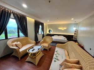 a hotel room with a bed and chairs and a living room at Fair Park Premier in Ipoh