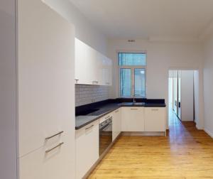 a kitchen with white cabinets and a wooden floor at Central and modern Valletta flat in Valletta