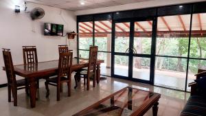 a dining room with a wooden table and chairs at Spill View Villa in Minneriya
