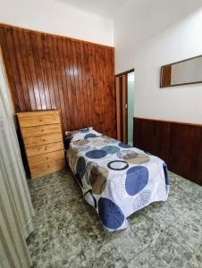 ein Schlafzimmer mit einem Bett und einer Holzwand in der Unterkunft Rincón Libertad 1 in Villa Mercedes