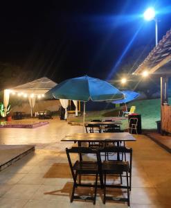 a picnic table with a blue umbrella at night at Das Marias Hostel in Lagoa Santa