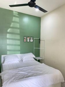 a bedroom with a white bed and a ceiling fan at Rumah Aidin Homestay in Sitiawan