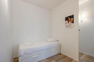 ein weißes Schlafzimmer mit einem Bett und einem Spiegel in der Unterkunft Marais Renard in Paris