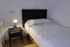 a small bedroom with a bed and a lamp at Piso Masip in Oviedo