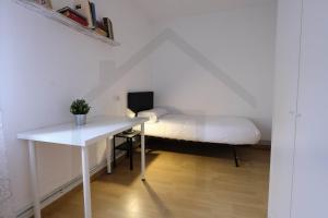 a white bedroom with a bed and a desk at Piso Masip in Oviedo