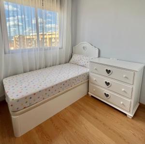 a crib in a room with a window and a dresser at Apartamento apto para bebés con parking privado in Almazora