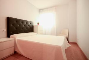 1 dormitorio con 1 cama con cabecero negro y ventana en Apartamento apto para bebés con parking privado en Almazora