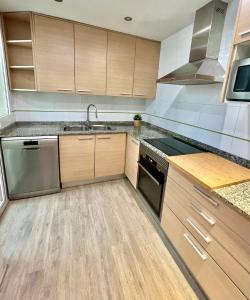 una cocina con electrodomésticos de acero inoxidable y armarios de madera en Apartamento apto para bebés con parking privado en Almazora