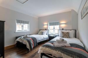 a bedroom with two beds and two windows at SandiComplex - 2 properties joined by a garden gate in Sandwich