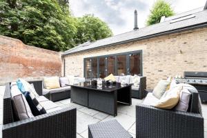 a patio with couches and a table and a grill at SandiComplex - 2 properties joined by a garden gate in Sandwich