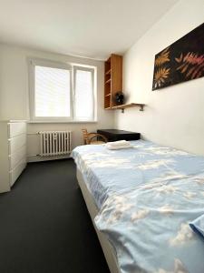 a bedroom with two beds and a desk and window at Cozy, bright room with free parking in Bratislava