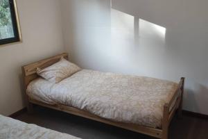 Cama pequeña en habitación con pared blanca en Cabañas en la naturaleza, en Villarrica