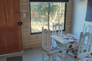 1 mesa y 2 sillas en una habitación con ventana en Cabañas en la naturaleza, en Villarrica