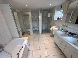 a bathroom with two sinks and a tub and a toilet at Ferienhaus Konze in Hilchenbach