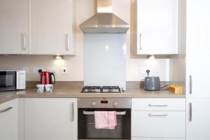 una cucina con armadi bianchi e piano cottura di Cosy Home with Garden in a Picturesque Village a Hull